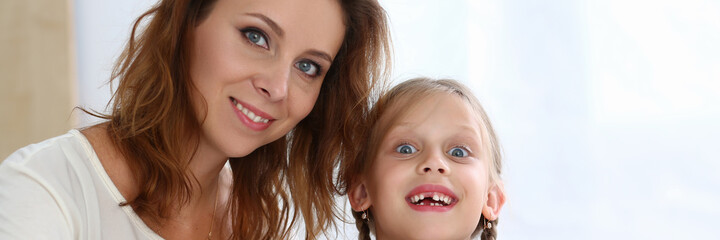 Obraz premium Portrait of cheerful woman with her child while they are sitting at table and reading book