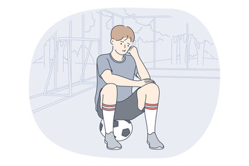 Professional football player, soccer ball, sport concept. Young unhappy boy football player sitting on soccer ball and feeling sad after failure during workout or game. Sport, athletics, team sport 