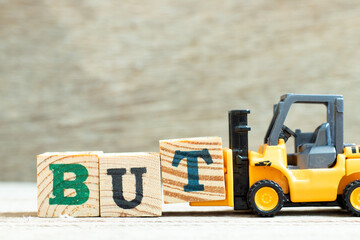 Toy forklift hold letter block t to complete word but on wood background