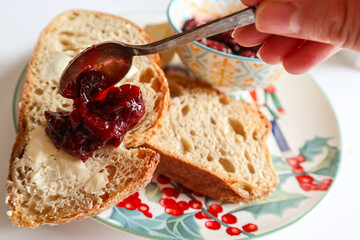 Woman spreading sweet jam on toast over table, top view
