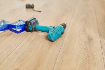 Close up of electric drill and carpenter tools on wooden floor