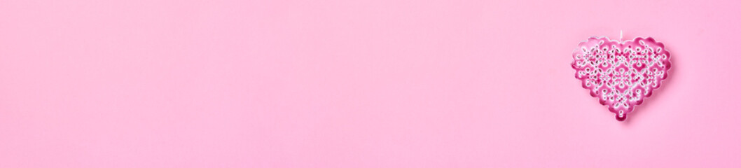 Beautiful openwork decorative heart on a pink background wall. Valentine day greeting card. Banner. Top view.