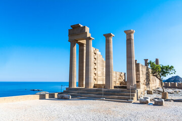 ruins of the ancient acropolis temple in greece on a sunny day with plain blue sky background