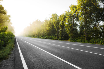 Fototapeta premium The asphalt road outside the city and thick fog above it in the morning