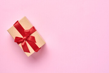 Beautiful gift box with red ribbon on a pink background wall. Valentine day greeting card. Top view.