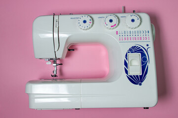 White sewing machine on a pink background. Electric sewing machine. Handmade tool. Sewing business.