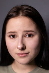 portrait of charming scared brunette woman in marsh color t-shirt on grey wall background. actress acting, emotion