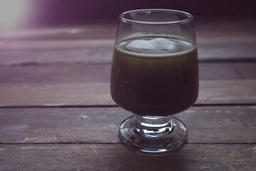 Wine glasses has hot Matcha green tea,and has collagen powder on top,on old wood table top,natural dimly light,selective focus.Concept of relaxation with healthy tea.