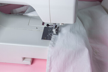 White sewing machine on a pink background. Electric sewing machine. white fabric on the sewing machine. Handmade tool. Sewing business.