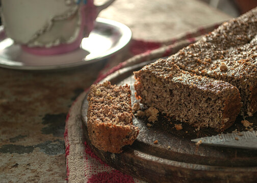 bud&iacute;n integral y artesanal sobre un plato de madera, tocado por un haz de luz que entra por la ventana y con tazas de te alrededor