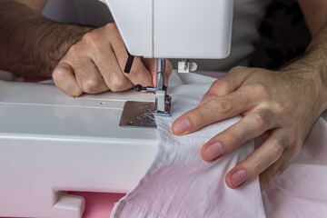 Obraz na płótnie Canvas White sewing machine on a pink background. Electric sewing machine. Hands for work on the sewing machine. Handmade tool. Sewing business.