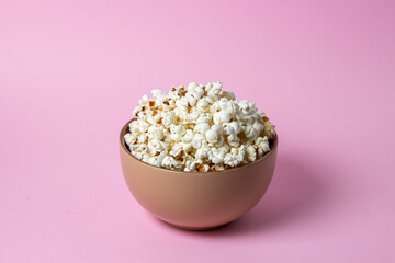 Popcorn on a pink background. A full plate of popcorn. Movie snack.