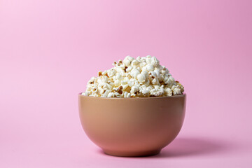 Popcorn on a pink background. A full plate of popcorn. Movie snack.
