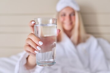 Glass of clean water close-up in hand of young woman