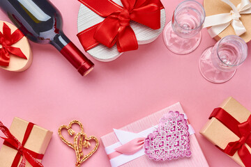 Wine, glasses and gift box in the form of heart with a red ribbon on pink background. Valentines day concept postcard. Top view.
