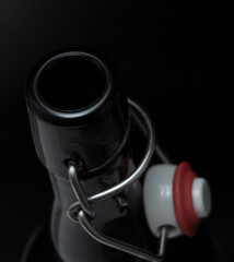 Neck of a bottle on a black background with a red beer stopper.