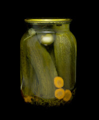glass jar of pickled cucumbers on black background