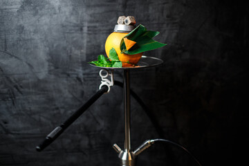 fruit hookah on grapefruit with mint leaves and bamboo on a dark gray background close-up. concept for hookah bar. copy space