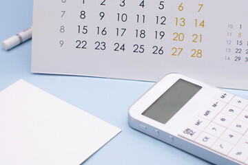 white calculator, calendar and note paper on blue background