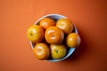 clementines in a bowl with orange background