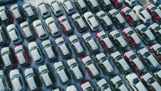 Aerial top down view of new cars parked in car parking lot. Car dealer parking lot full of new automobiles. New cars lined up for import and export business.