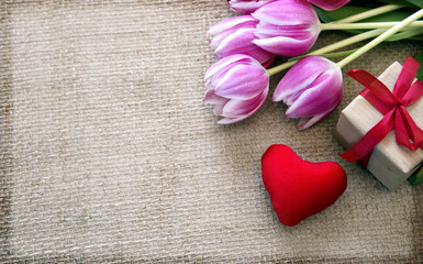 Obraz na płótnie Canvas Valentine's day background with tulips and red heart on cloth Background.