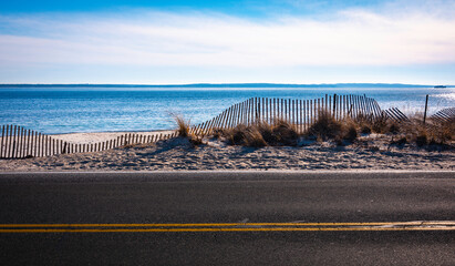 Seascape topography with curved snow fence over the sand dune along the coastal road