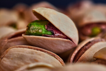 Close-up of green pistachio with open shell, next to more pistachios