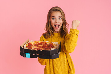Excited girl showing winner gesture while posing with pizza