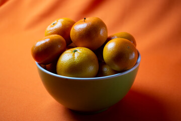 clementines in a bowl with orange background
