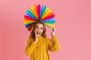 Obraz na płótnie Canvas Joyful girl smiling while posing with multicolored fan on her head