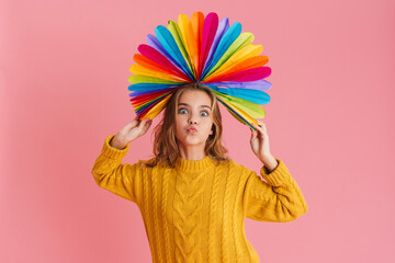Obraz na płótnie Canvas Joyful girl grimacing while posing with multicolored fan on her head