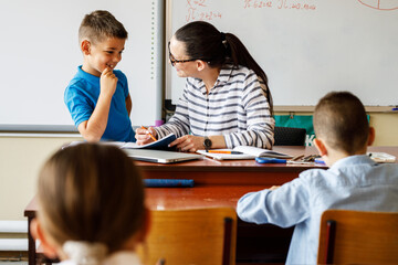 Female teacher helps her student to resolve mathematics assignment .	
