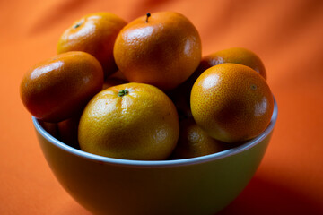 clementines in a bowl with orange background