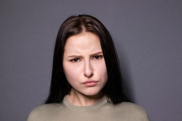 portrait of charming shocked brunette woman in marsh color t-shirt on grey wall background. actress...