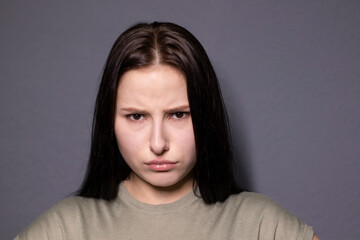 Fototapeta premium portrait of charming shocked brunette woman in marsh color t-shirt on grey wall background. actress acting, emotion