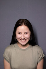 portrait of charming happy brunette woman in marsh color t-shirt on grey wall background. actress acting, emotion.