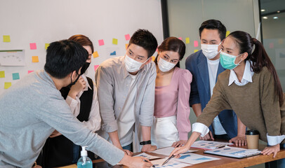 Group of business office worker team meeting and brainstorm for startup new business. man and woman wearing face mask protective in new normal office preventing coronavirus COVID-19 spreading.