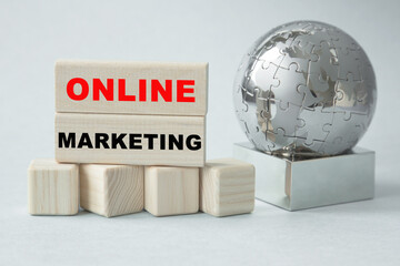 Text ONLINE MARKETING . Globe and wooden cubes on a gray background. The concept of world business, marketing, finance.
