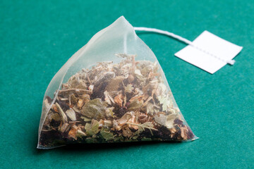 
Herbal tea pyramid isolated on green background. Close-up