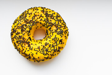 Close-up shot of a bright, tasty yellow donut with chocolate splashes on a white background