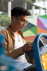 young hispanic man with glasses, reading a book while using the bus to go to work, listening to music on his headphones © Patricio