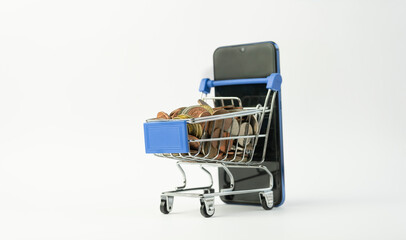 Shopping cart full of coins with a smart phone.Money and financial. E-commerce business marketing online shopping ,mini supermarket trolley on isolated white background.Save and spend money concept.