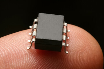 A tiny microchip on the finger of a man's hand on a black background.extreme close-up.The concept...