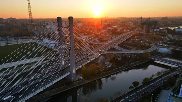Ciurel passage, bridge over a river with moving cars, field and TV tower near it. Residential buildings on the background. View from the drone, sunset. Bucharest, Romania