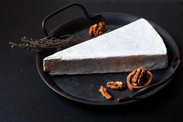 Food concept French Soft Brie cheese in rustic iron plate on black slate stone background with copy space