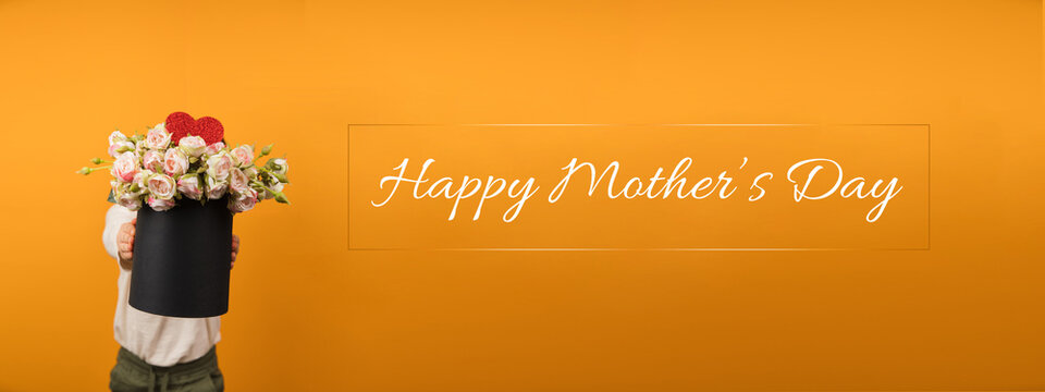 Greeting Card For Mothers Day. Faceless Little Boy Giving Flowers And Heart Shape To Camera. Handwriting Calligraphy With Happy Mother's Day Words. Horizontal Banner With Copy Space.