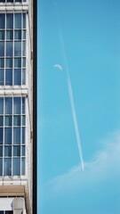 blue sky with plane flying past with moon in the background