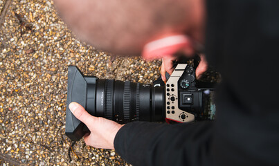 Close up view of a photo video mirrorless camera held in hand by a male photographer in nature...