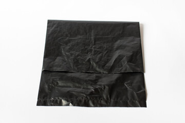 Large black crumpled folded plastic bag on white background.